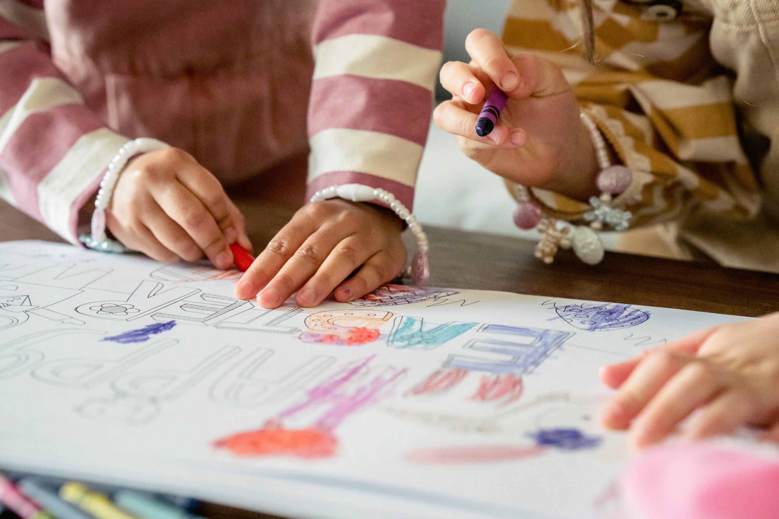 2 enfants colorient avec des crayons de cire